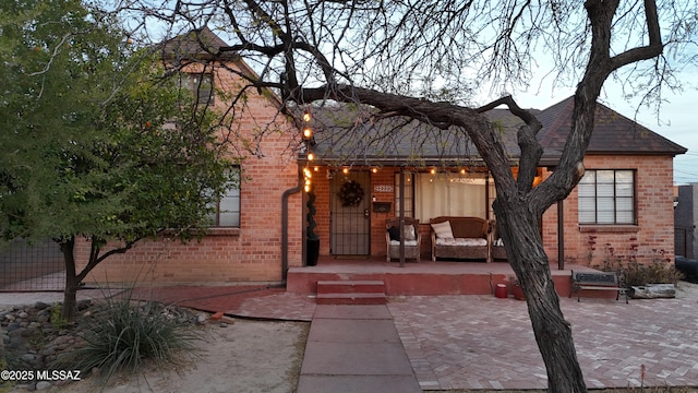 view of front of home featuring brick siding and a patio