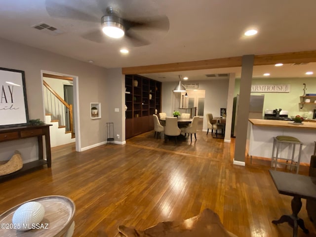 living area featuring recessed lighting, visible vents, hardwood / wood-style floors, baseboards, and stairs