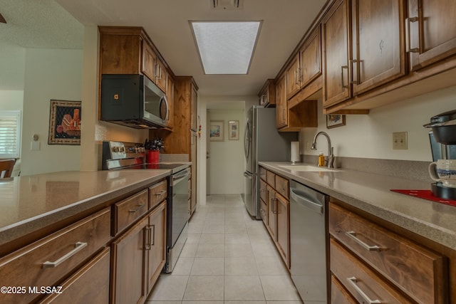 kitchen with light tile patterned floors, visible vents, appliances with stainless steel finishes, brown cabinets, and a sink