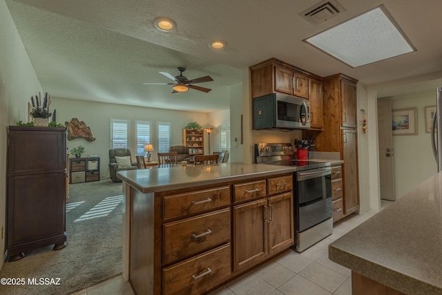 kitchen featuring light tile patterned floors, light colored carpet, stainless steel appliances, a ceiling fan, and visible vents