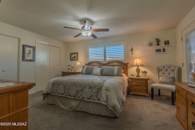 carpeted bedroom with two closets, ceiling fan, and a textured ceiling