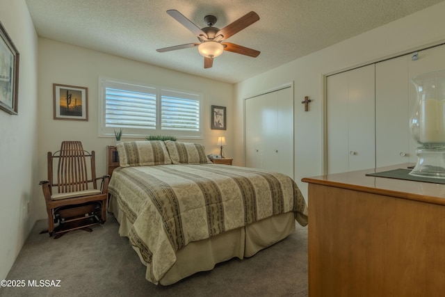 bedroom with a textured ceiling, carpet, a ceiling fan, and multiple closets