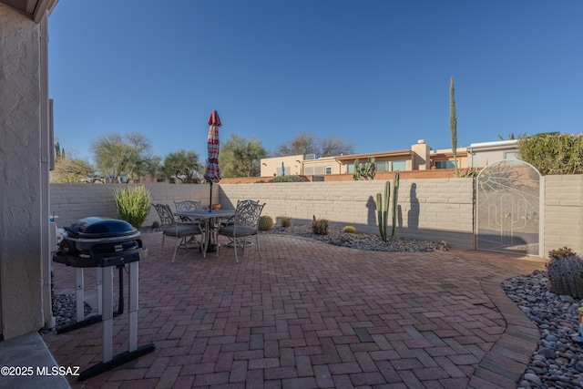 view of patio with outdoor dining area, a fenced backyard, and a grill