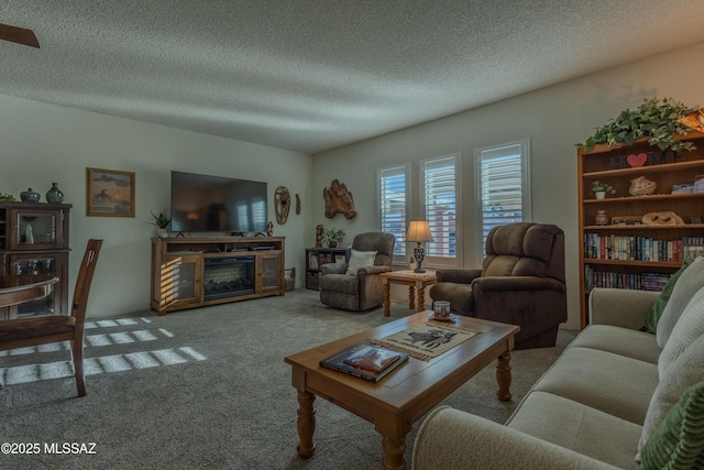 living area featuring carpet, a glass covered fireplace, and a textured ceiling