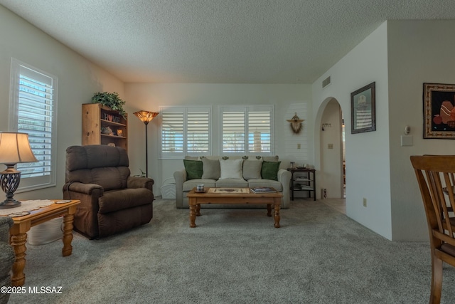 living room featuring a healthy amount of sunlight, carpet floors, visible vents, and arched walkways