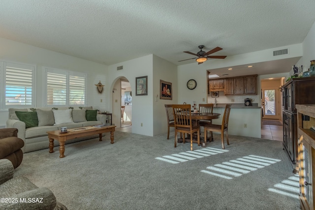 living room featuring a healthy amount of sunlight, light carpet, visible vents, and arched walkways