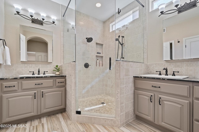 bathroom featuring two vanities, a sink, tile walls, and a shower stall