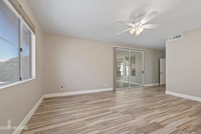 empty room with light wood finished floors, baseboards, visible vents, and ceiling fan