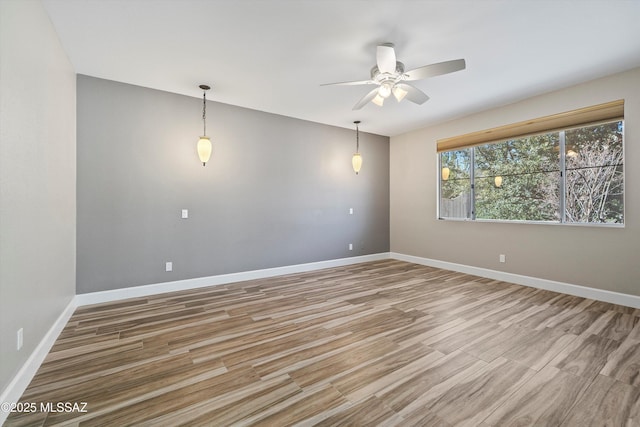 unfurnished room with light wood finished floors, a ceiling fan, and baseboards