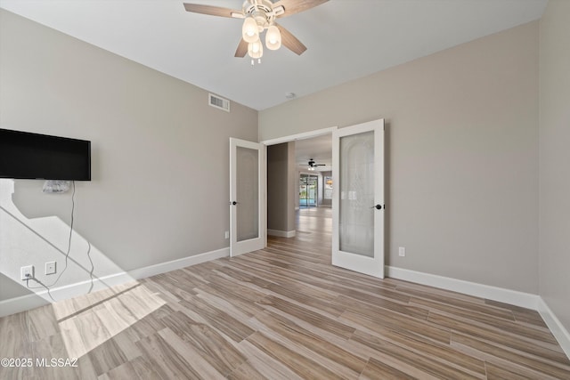 unfurnished room with ceiling fan, visible vents, baseboards, light wood-style floors, and french doors