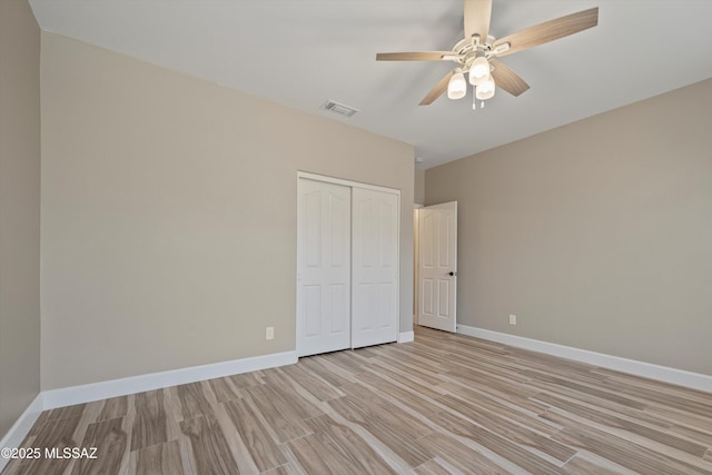 unfurnished bedroom featuring a closet, visible vents, light wood-style flooring, a ceiling fan, and baseboards