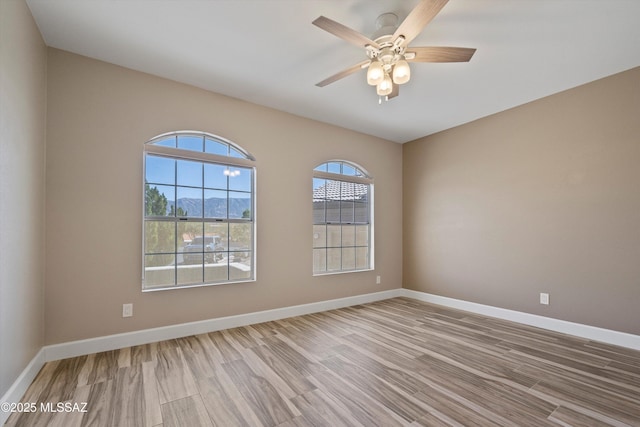 unfurnished room featuring a ceiling fan, baseboards, and wood finished floors