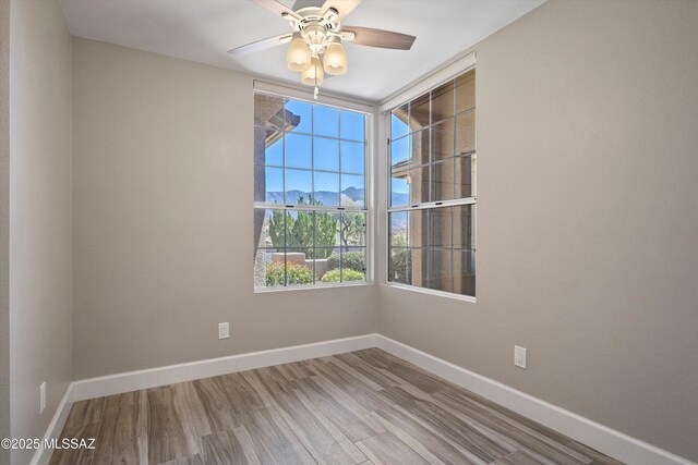 empty room with a ceiling fan, baseboards, and wood finished floors