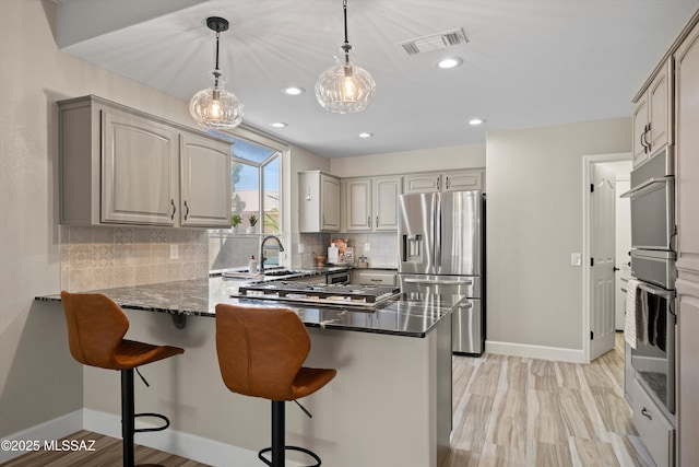 kitchen with tasteful backsplash, visible vents, a sink, a peninsula, and stainless steel fridge with ice dispenser