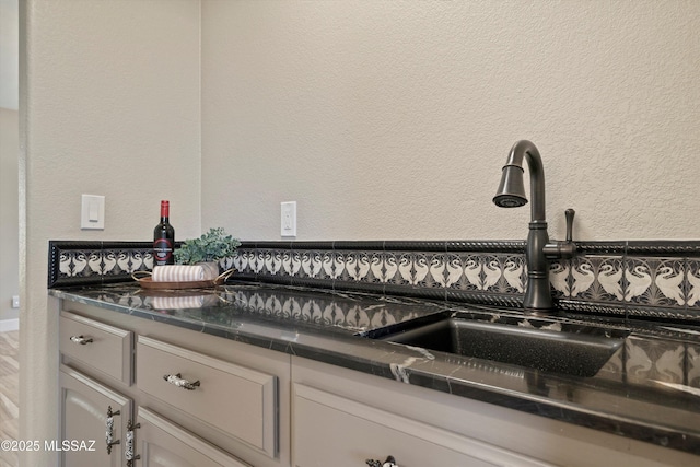 room details with dark countertops, white cabinetry, and a textured wall