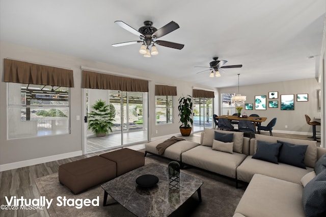 living room with ceiling fan with notable chandelier, wood finished floors, and baseboards