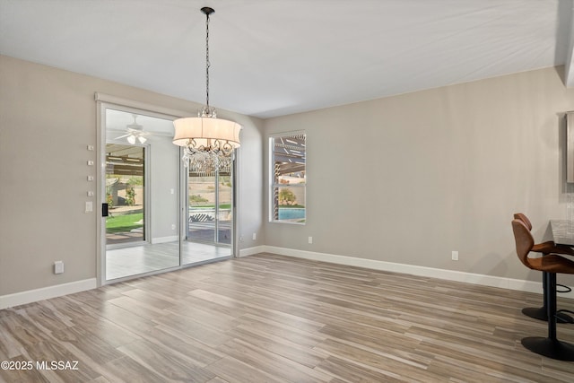 unfurnished dining area featuring light wood-style flooring and baseboards