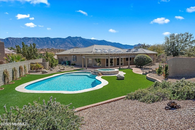 view of swimming pool featuring a fenced backyard, a yard, a patio area, a pool with connected hot tub, and a mountain view