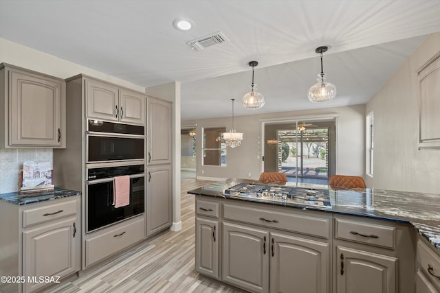 kitchen with stainless steel gas cooktop, dark stone counters, visible vents, and dobule oven black