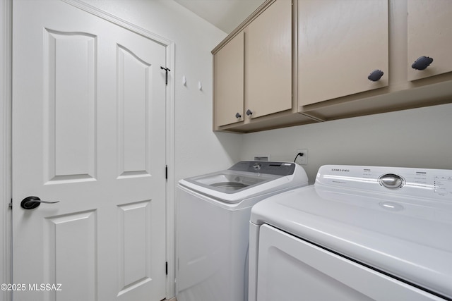 clothes washing area with separate washer and dryer and cabinet space