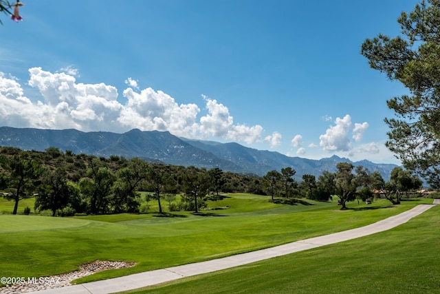 view of community with a yard, view of golf course, and a mountain view