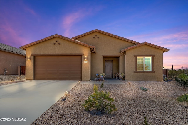 view of front of property featuring concrete driveway, a tiled roof, an attached garage, and stucco siding