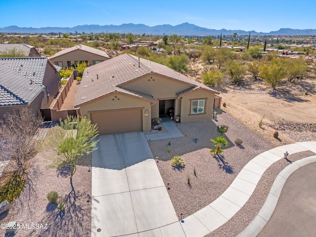 view of front of home featuring a garage, concrete driveway, a tiled roof, a mountain view, and stucco siding