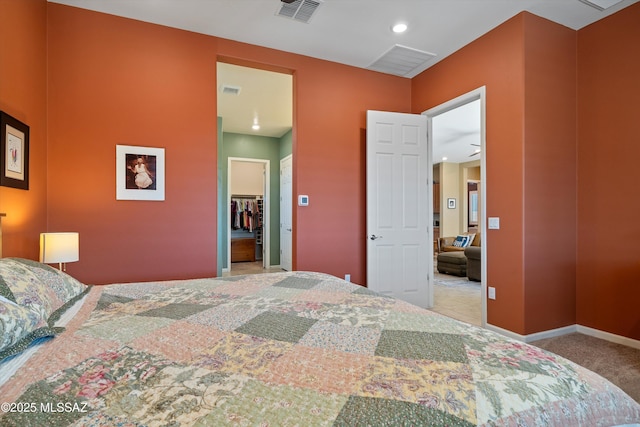 bedroom with visible vents, baseboards, carpet, a walk in closet, and a closet