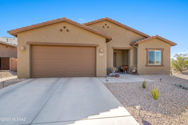 view of front of home with a garage, concrete driveway, a tile roof, and stucco siding