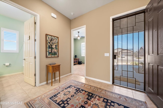 foyer entrance featuring baseboards, ceiling fan, and light tile patterned floors