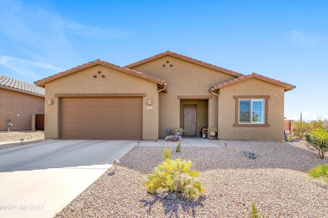 mediterranean / spanish house featuring concrete driveway, an attached garage, a tiled roof, and stucco siding