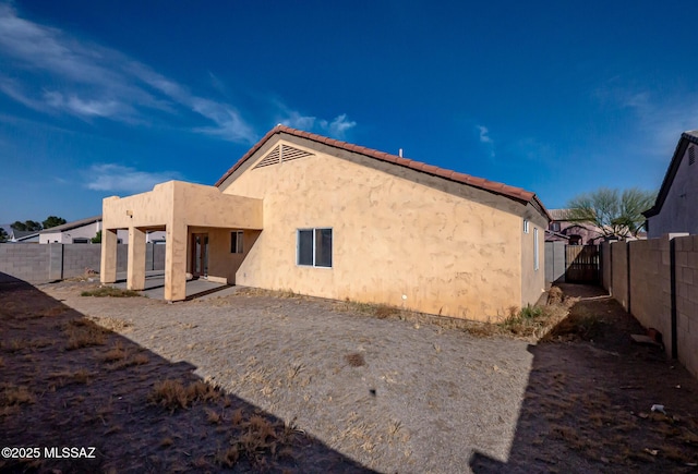 back of house featuring a fenced backyard, a patio, and stucco siding