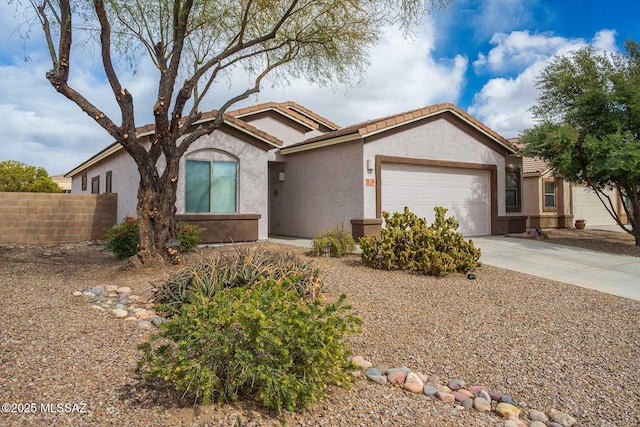 ranch-style home with an attached garage, fence, concrete driveway, a tiled roof, and stucco siding