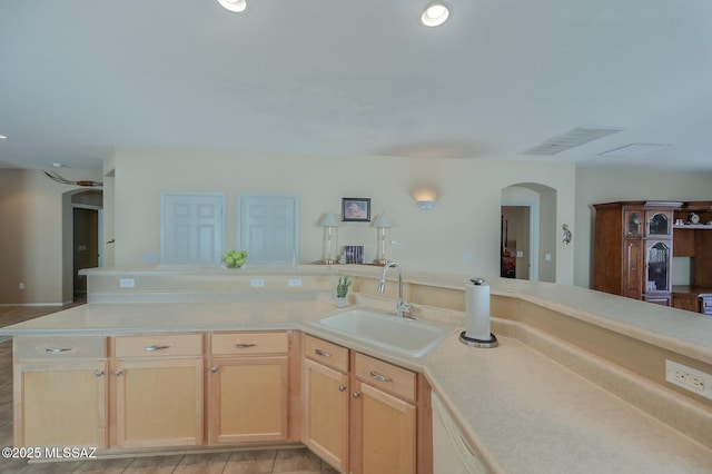 kitchen featuring visible vents, arched walkways, light countertops, and a sink