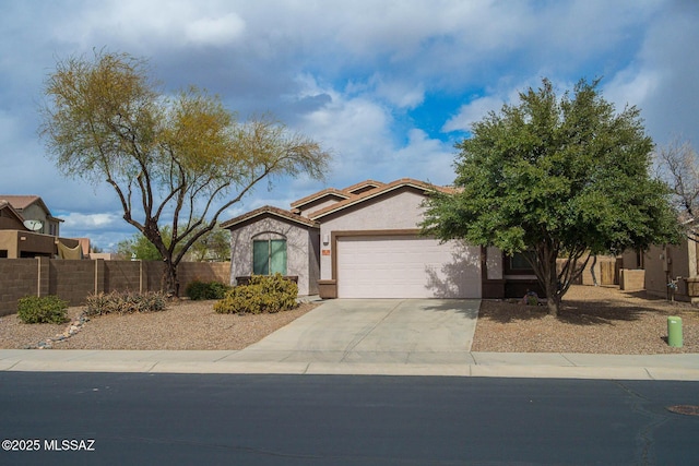 view of front of house with stucco siding, concrete driveway, an attached garage, fence, and a tiled roof