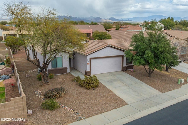 ranch-style home featuring a mountain view, a tiled roof, an attached garage, and stucco siding