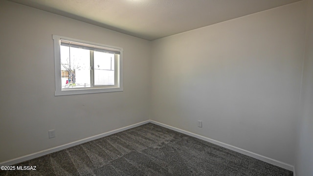 empty room with baseboards and dark colored carpet