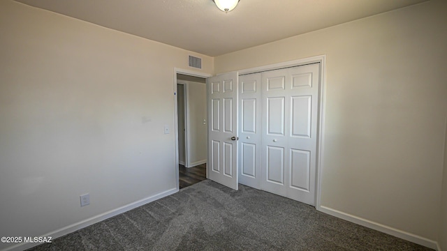 unfurnished bedroom featuring dark colored carpet, visible vents, baseboards, and a closet