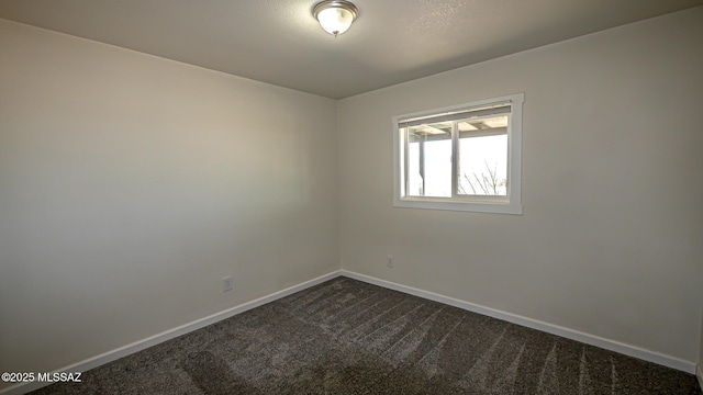 unfurnished room with baseboards and dark carpet