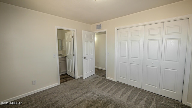 unfurnished bedroom with dark colored carpet, visible vents, baseboards, and a closet