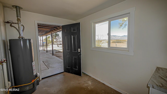 doorway featuring gas water heater, a healthy amount of sunlight, baseboards, and concrete flooring