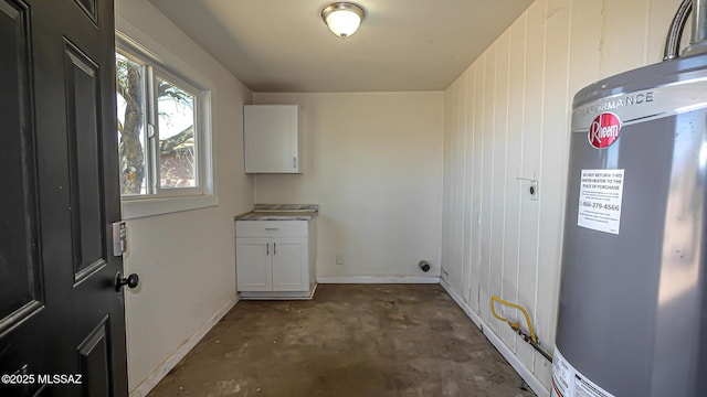 washroom with baseboards and water heater