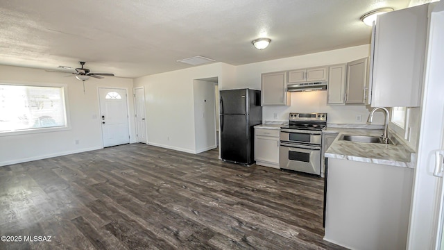 kitchen featuring under cabinet range hood, a sink, freestanding refrigerator, light countertops, and range with two ovens