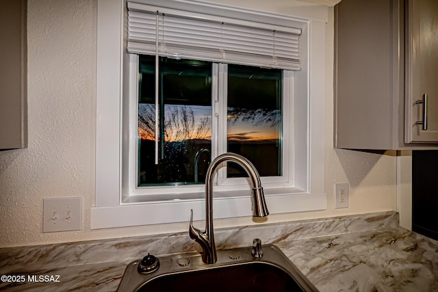 details with a sink, gray cabinetry, light countertops, and a textured wall