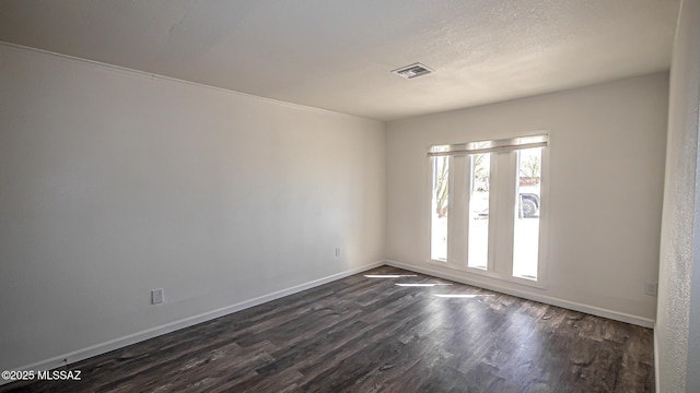 spare room featuring visible vents, baseboards, a textured ceiling, and dark wood-style floors