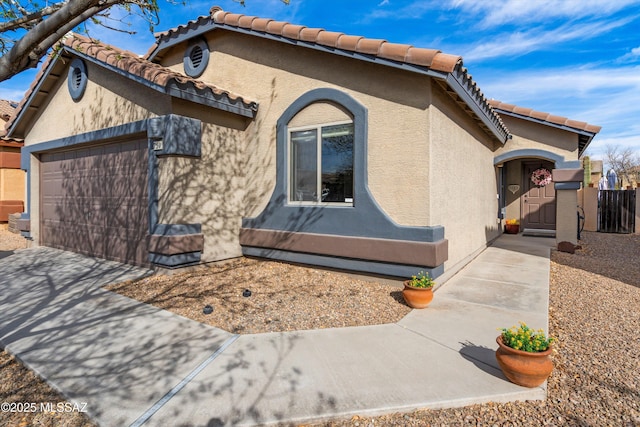 view of front of home with driveway, a tiled roof, an attached garage, and stucco siding