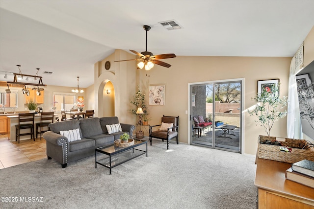 living room featuring light carpet, visible vents, arched walkways, and ceiling fan with notable chandelier