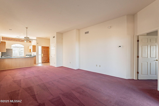 unfurnished living room with ceiling fan, visible vents, and carpet flooring