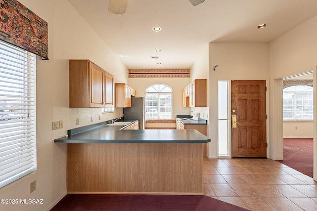 kitchen with white electric stove, light tile patterned floors, dark countertops, and a sink