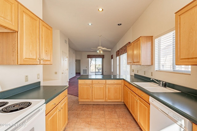 kitchen featuring white appliances, a ceiling fan, dark countertops, a peninsula, and a sink